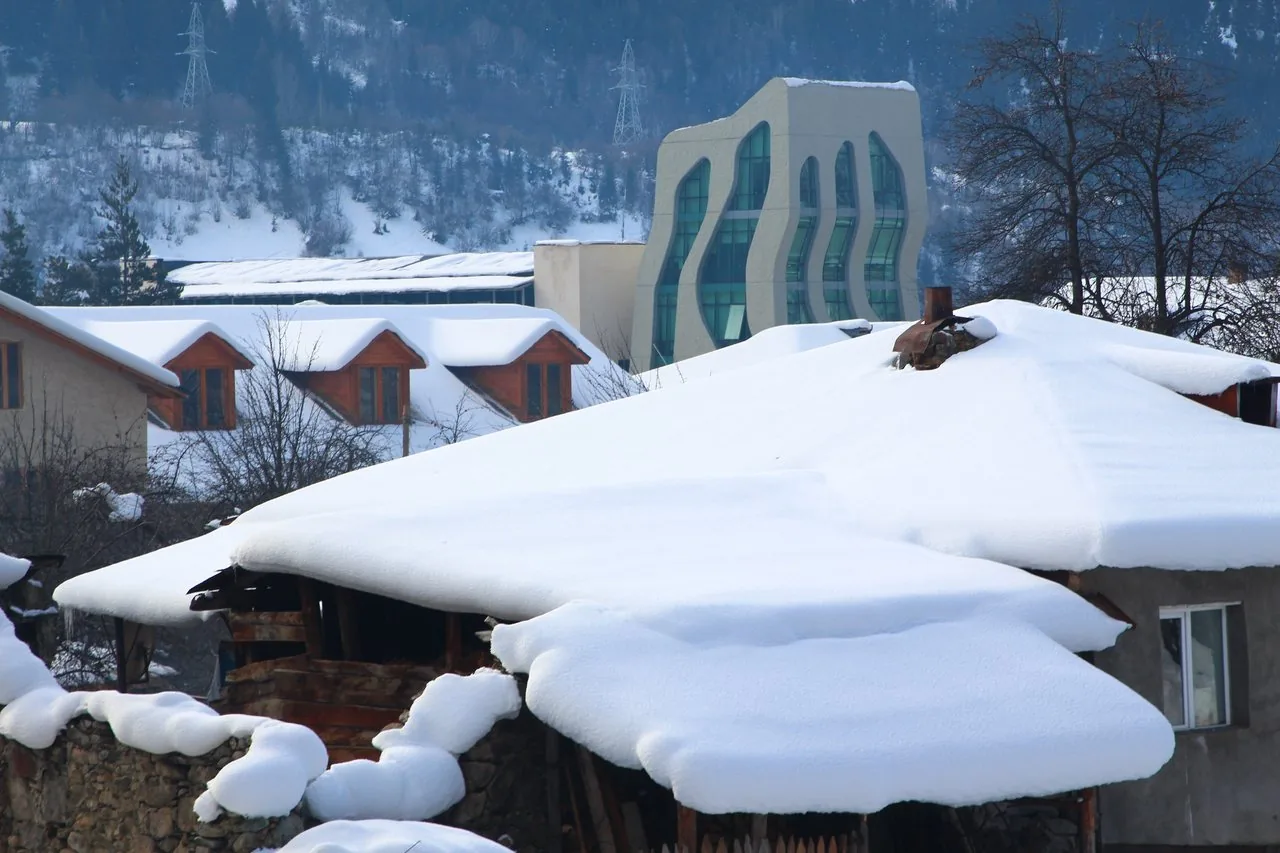 Snow-covered roofs and Caucasus mountains around Mestia in winter